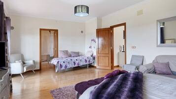 Une chambre à coucher avec un lit, une chaise, un canapé, un miroir et un luminaire au plafond.