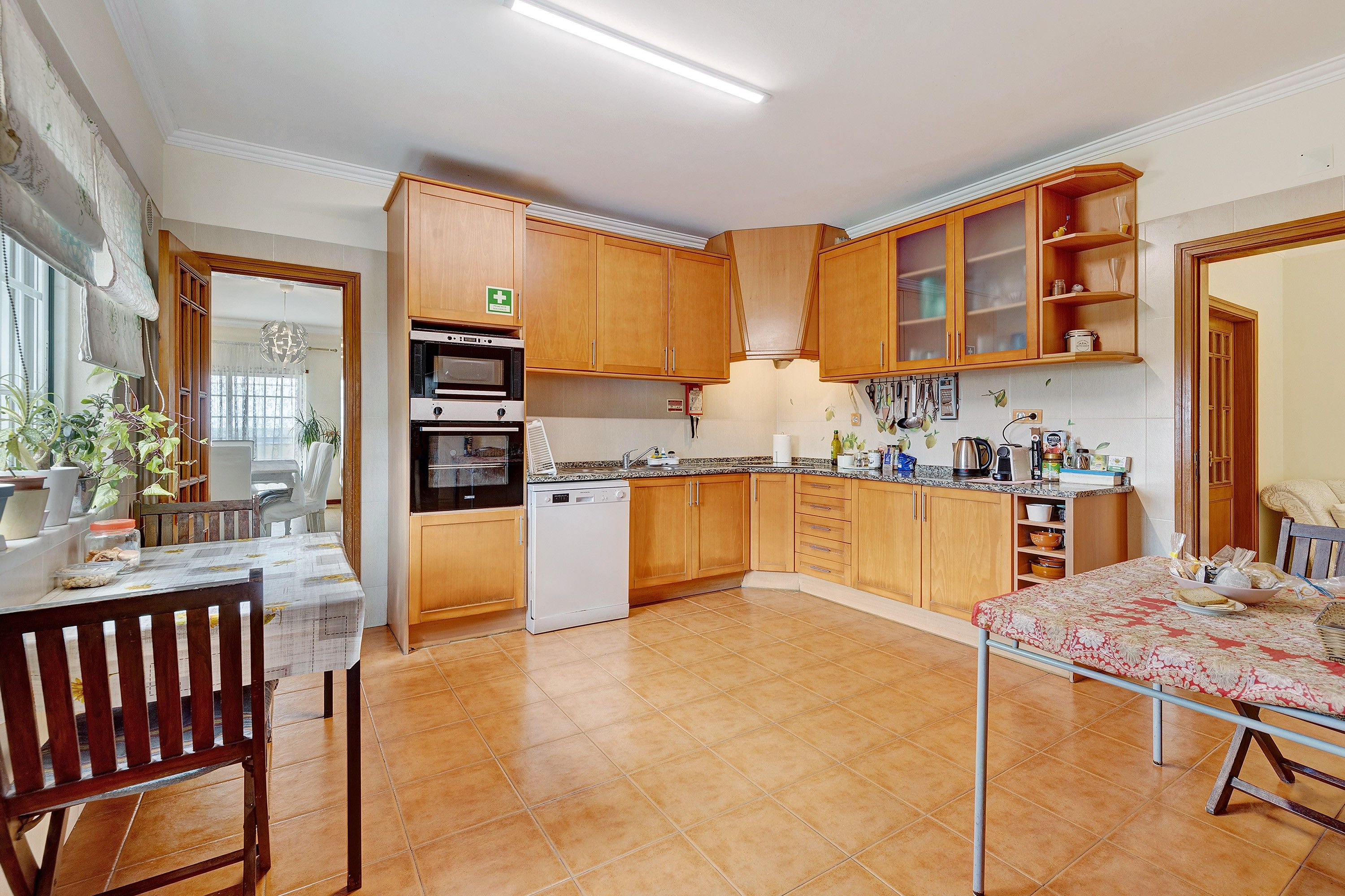 Een keuken met houten kastjes, een vaatwasser en een eethoek met een tafel en stoelen.