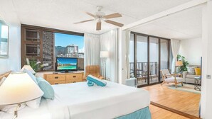 A hotel room with a bed, a TV, a balcony, and a city view.
