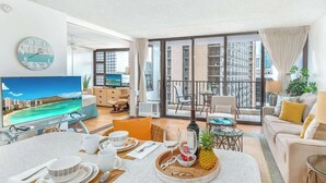 A modern living room with a dining area, large windows, and a balcony with a city view.