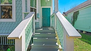 A green house with a teal door, white railings, and a number '3911' on the window. - The Minted Mermaid - Pet Friendly - Winter Texan Rates! (Galveston)