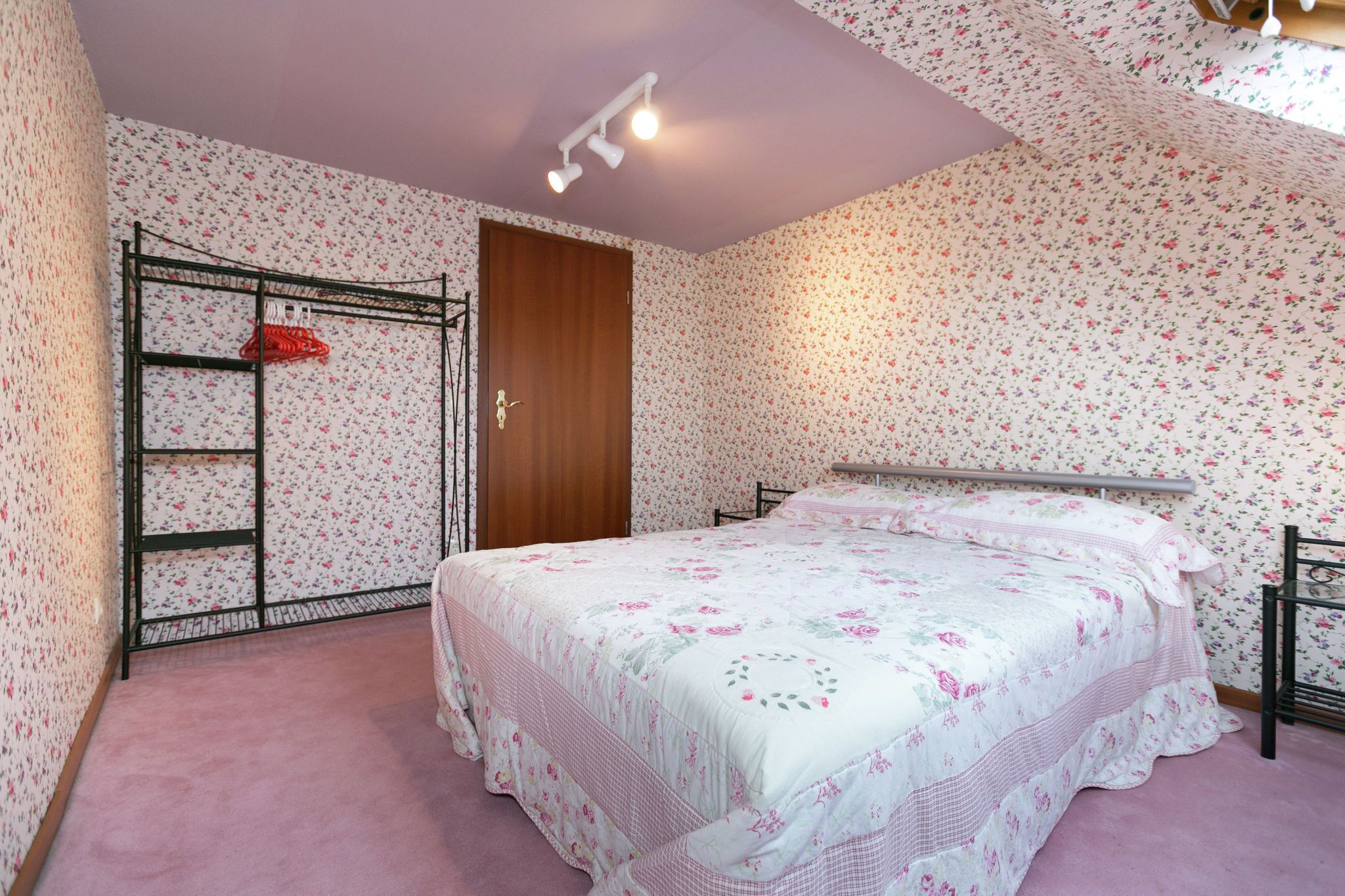 A bedroom with a bed, a wardrobe, and a door.