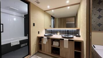Un baño moderno con ducha a nivel, tocador de madera con dos lavamanos y un espejo grande.
