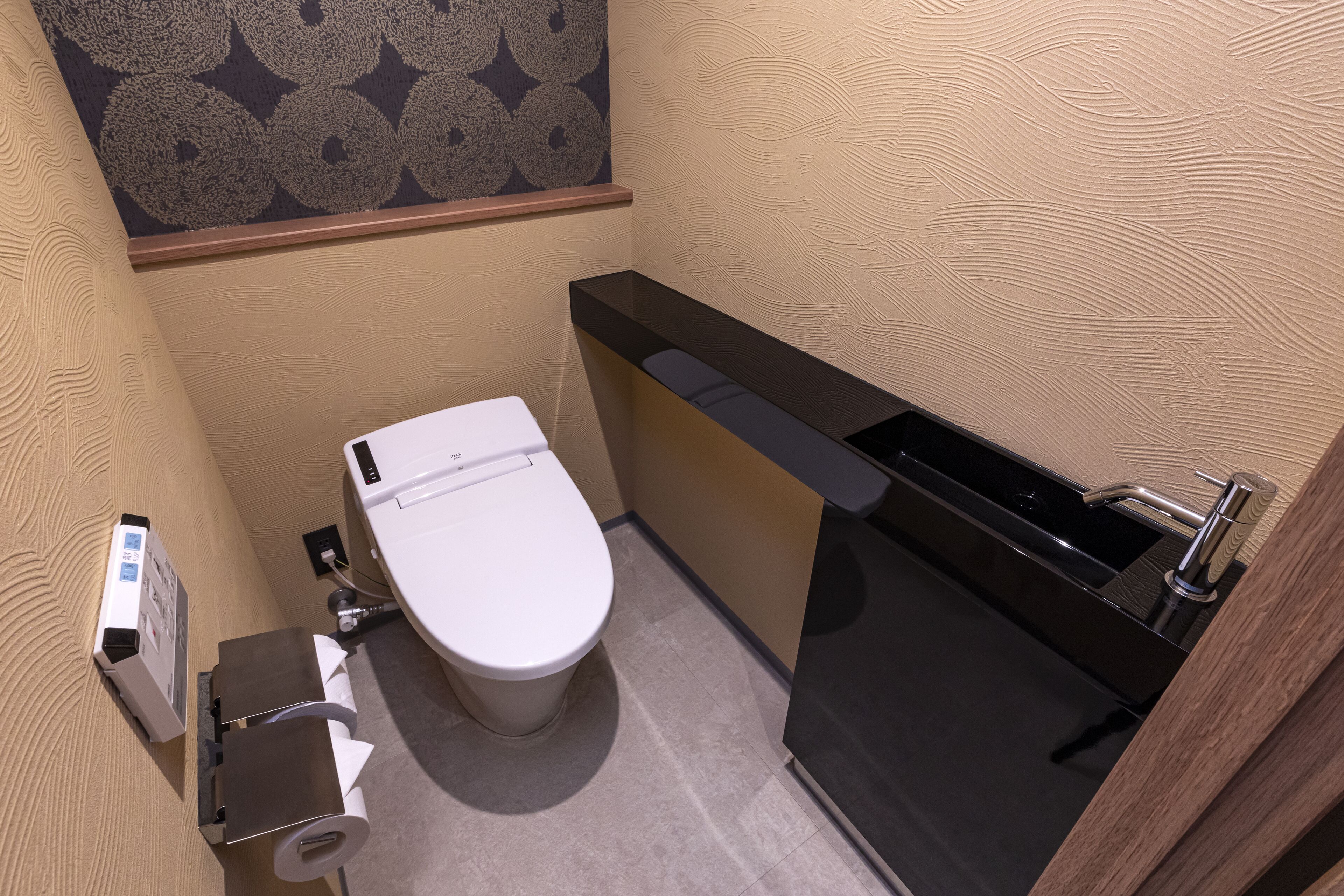 A compact bathroom with a toilet, a sink, and a paper towel dispenser.