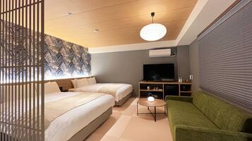 A modern hotel room with a large bed, a green sofa, a TV, and a ceiling light.