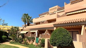 A hotel with a modern design, featuring multiple balconies and a well-maintained garden.