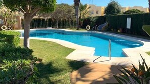 A swimming pool with a curved edge, surrounded by well-maintained grass and hedges.