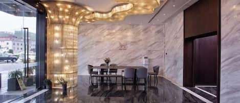 A modern interior with a marble wall, a dining area with a table and chairs, and a unique ceiling light fixture.