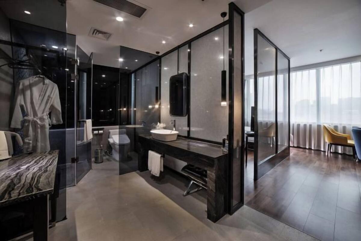 A modern bathroom with a glass-enclosed shower, a marble countertop, and a large mirror.