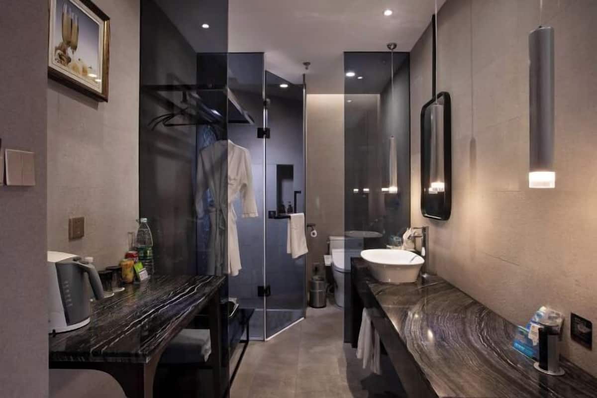 A modern bathroom with a glass shower enclosure, a marble countertop, and a large mirror.