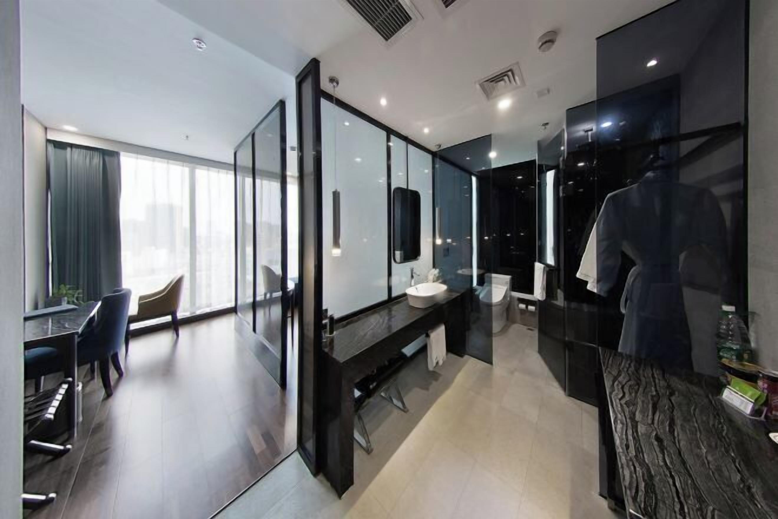 A modern hotel room with a large mirror, a desk, and a chair.