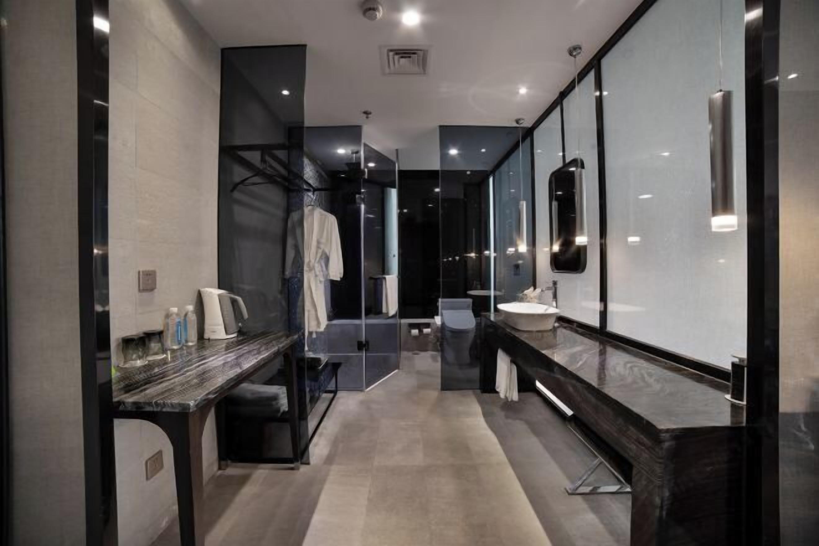 Une salle de bain moderne avec une douche à parois de verre, un comptoir en marbre et un grand miroir.