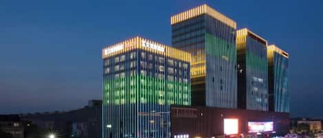 Un edificio de varios pisos con ventanas iluminadas y una entrada destacada.