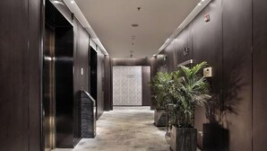 A modern elevator lobby with marble flooring and dark wood paneling. - Puyuan X Hotel (Tongxiang)
