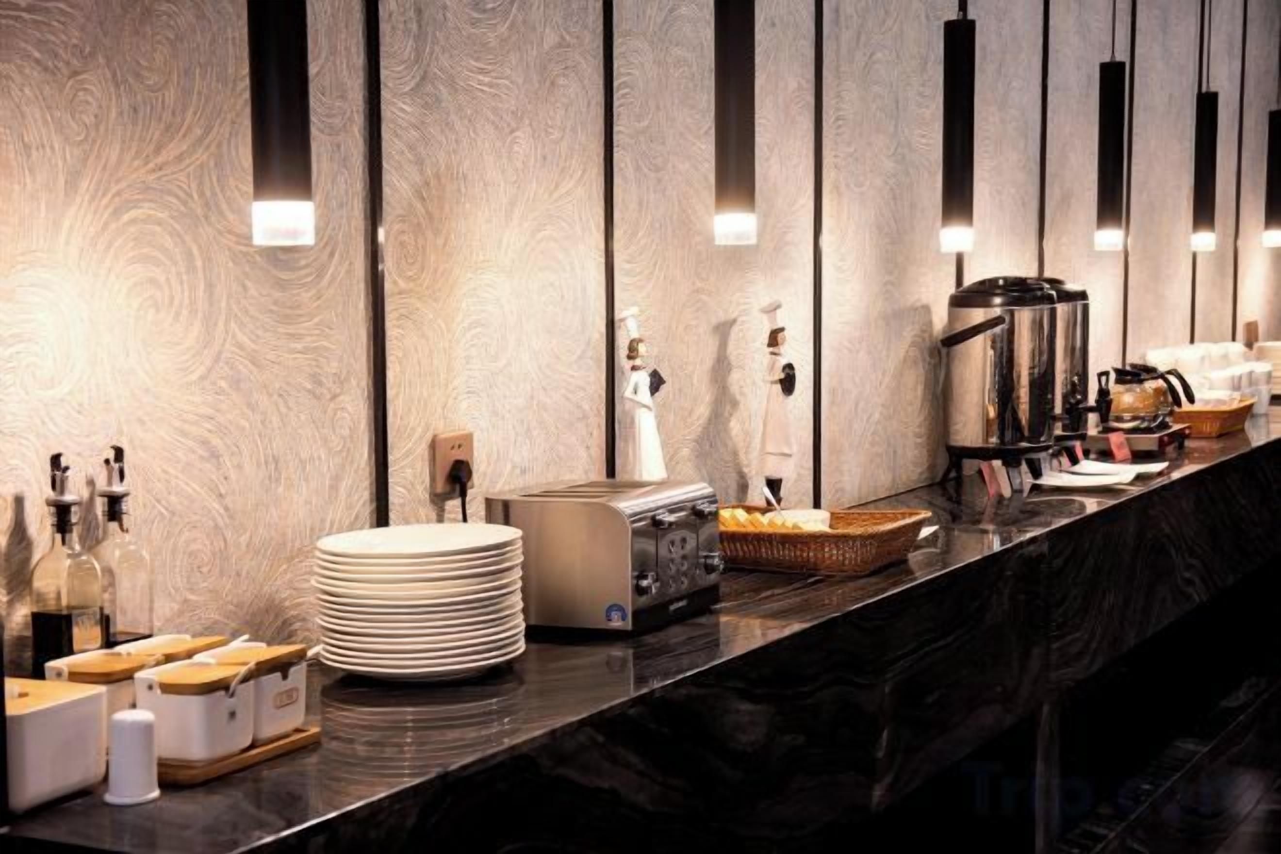 Zona de recepción de hotel con mostrador de mármol, una cafetera y una botella de jabón para manos.