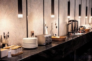 A hotel reception area with a marble counter, a coffee machine, and a bottle of hand soap. - Puyuan X Hotel (Tongxiang)