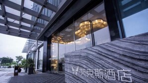 A modern hotel entrance with a marble facade and a glass canopy. - Puyuan X Hotel (Tongxiang)