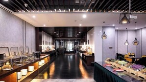 A modern hotel lobby with a long reception desk, a central seating area, and a buffet setup. - Puyuan X Hotel (Tongxiang)