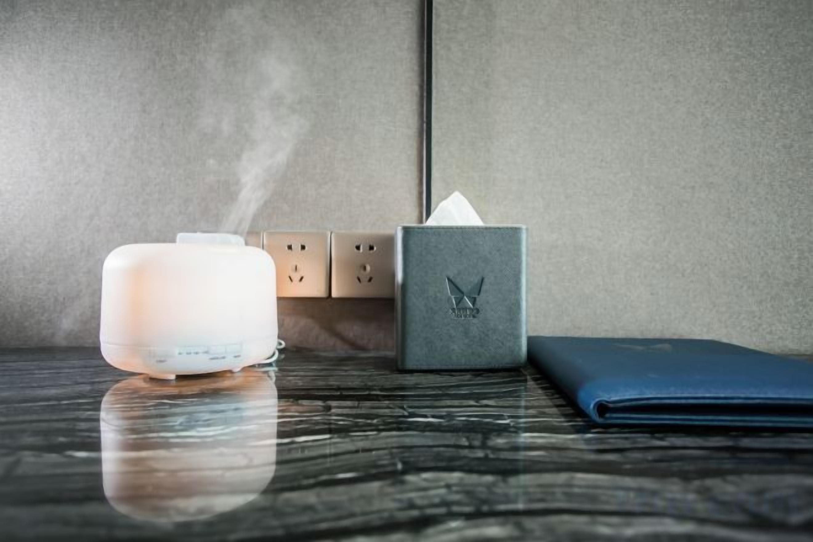 Una stanza con un umidificatore bianco, un portatovaglioli e un quaderno blu su un piano di marmo.