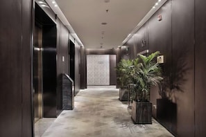 Un hall d’entrée moderne, doté d’ascenseurs, d’un sol en marbre et de plantes en pot.