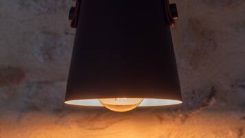 A hanging lamp with a wooden handle and a black shade, mounted on a textured wall.