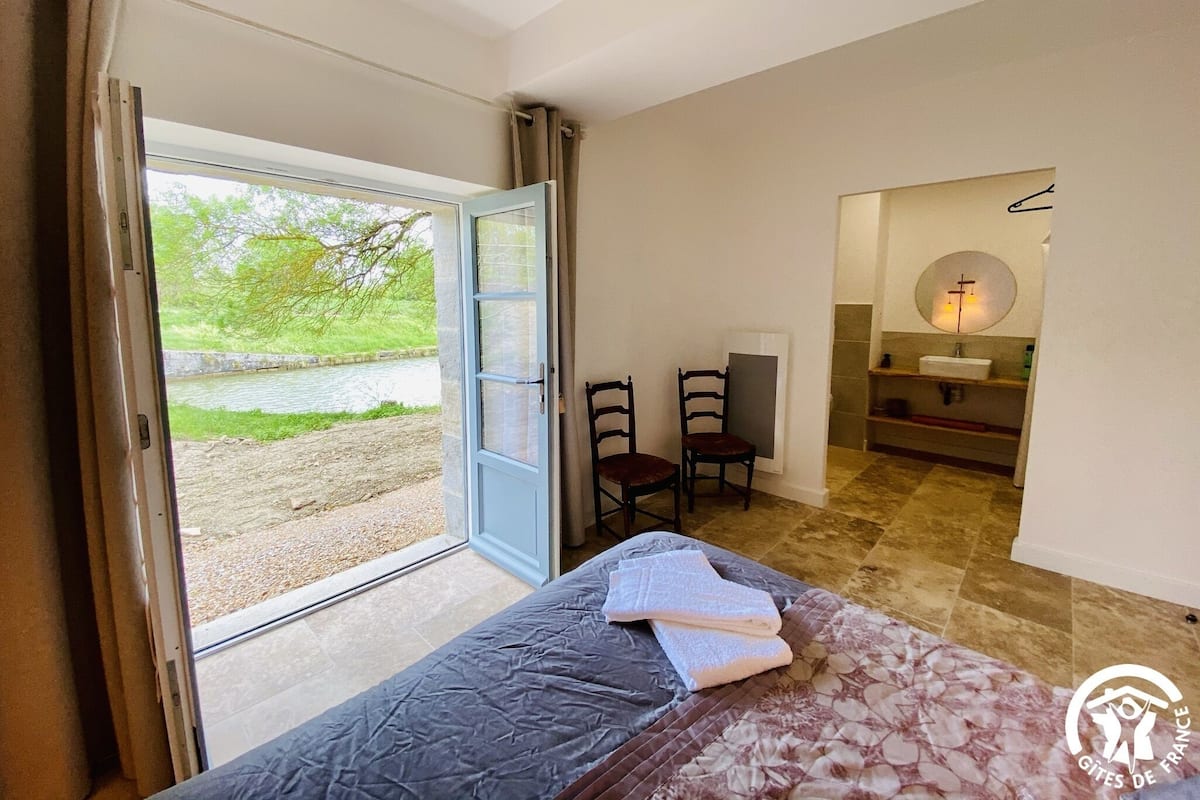 Une chambre à coucher comprenant un lit, une chaise, un bureau et une salle de bain avec un miroir et un lavabo.