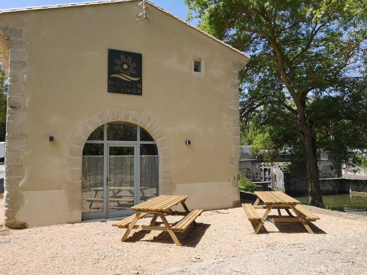 Un bâtiment sur lequel on peut lire l’inscription « Moulin du Vivier », avec deux tables de pique-nique à l’extérieur.