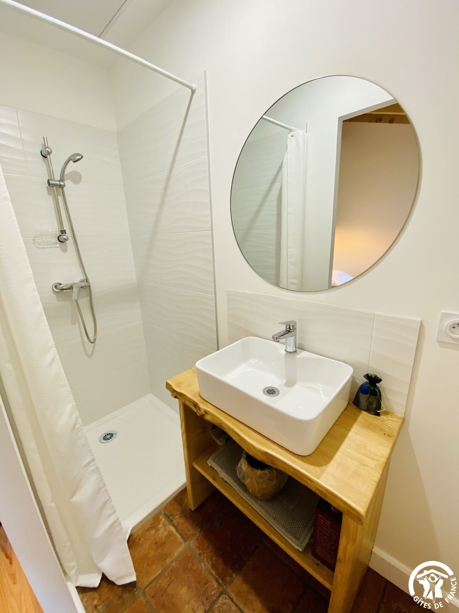 Une salle de bain avec un lavabo blanc, un miroir et une douche.
