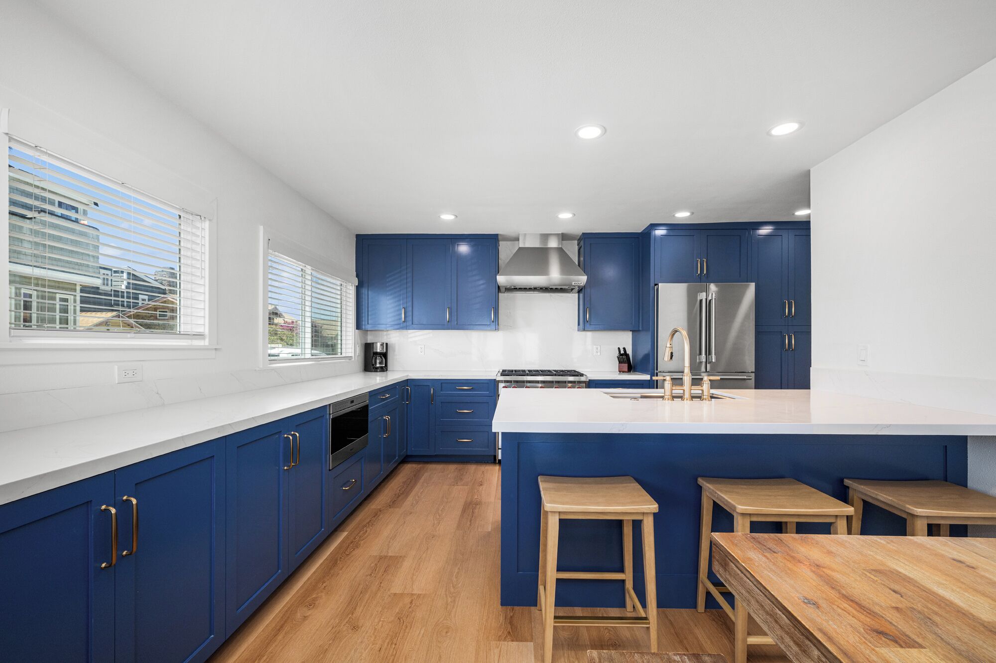 Una cucina moderna con mobili blu, un piano cottura in acciaio inossidabile e una grande isola con sgabelli.