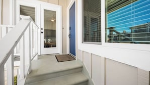 Una escalera que conduce a una puerta con ventana, timbre y felpudo.
