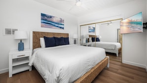 Un dormitorio moderno con una cama grande, mesitas de noche, ventilador de techo y obras de arte en las paredes.