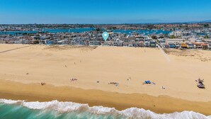 Vista aérea de una playa con casas, cielo despejado y olas.