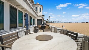 Una propiedad frente a la playa con una mesa en el patio, asientos exteriores y vistas al mar.