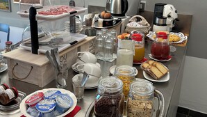 A buffet setup with various food items and beverages, including a coffee maker, a kettle, and a variety of spreads and condiments.