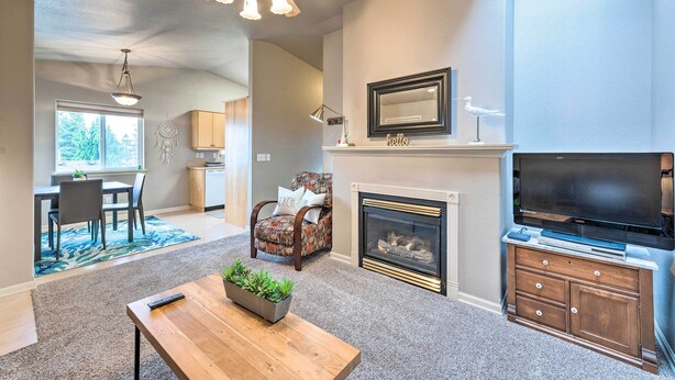 A living room with a fireplace, a television, and a dining area with a table and chairs. - Apartment w/ Patio & Grill Access ~ 1/2 Mi to Bay! (Anacortes)
