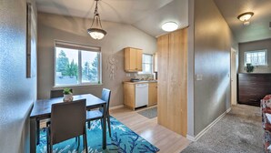 A modern kitchen with wooden cabinets, a dishwasher, and a dining area with a table and chairs. - Apartment w/ Patio & Grill Access ~ 1/2 Mi to Bay! (Anacortes)
