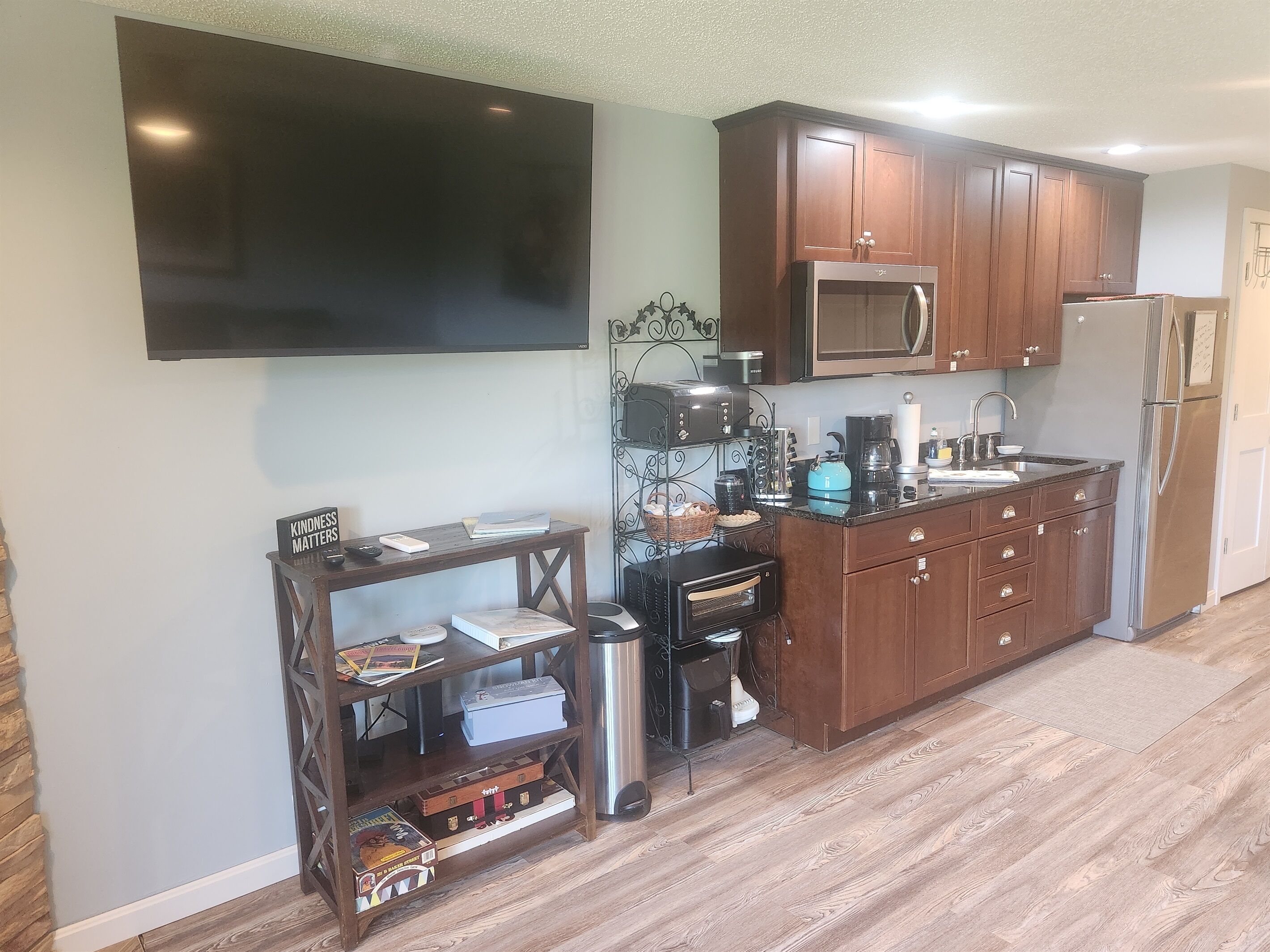 A modern kitchen with wooden cabinets, a microwave, a refrigerator, and a coffee maker.