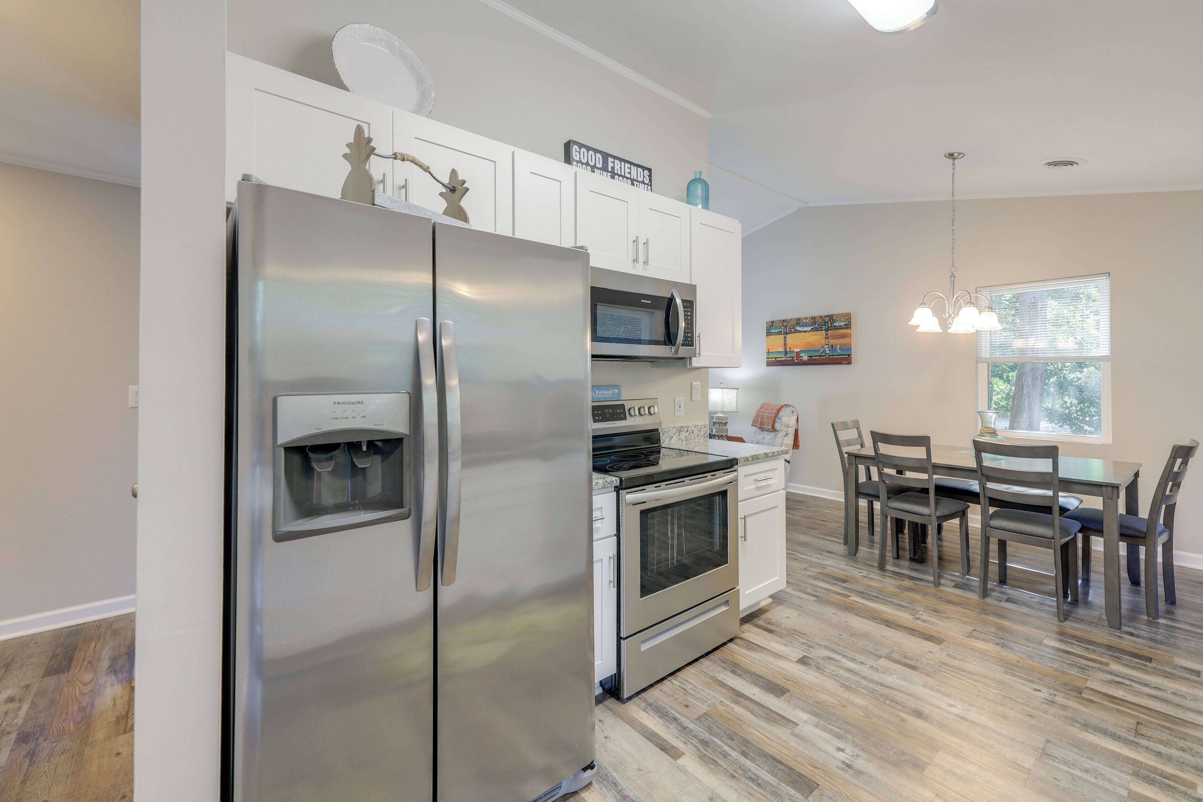 A modern kitchen with stainless steel appliances, white cabinetry, and a dining area with a table and chairs.
