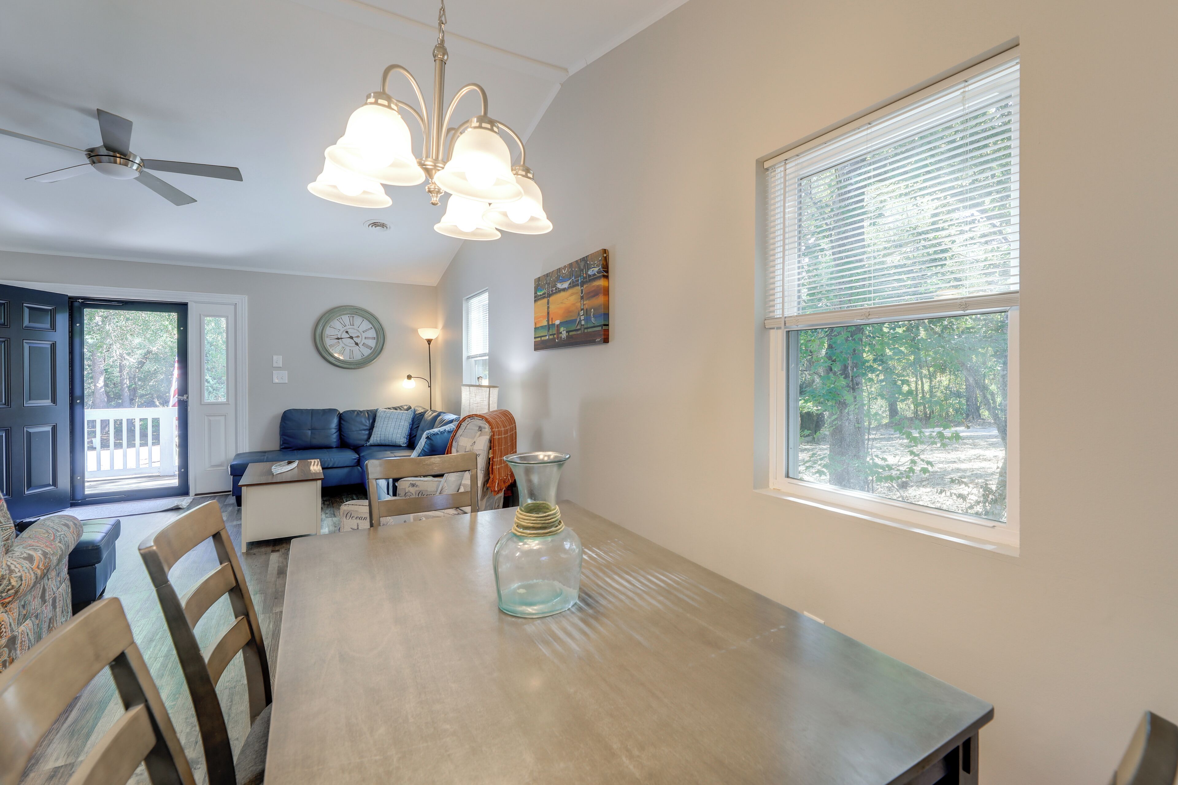 A dining area with a wooden table, chairs, a vase, and a ceiling fan.