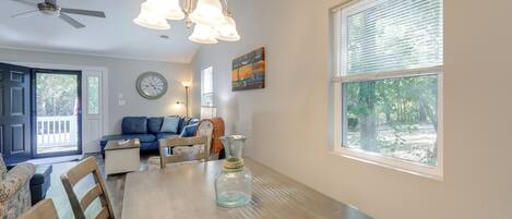 A dining area with a wooden table, chairs, a vase, and a ceiling fan.