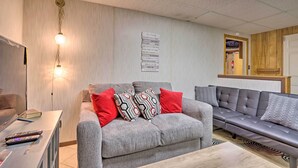 A modern living room with a grey sofa, red and patterned cushions, a wooden coffee table, and a ceiling light fixture. - Fish & Explore! Quiet Farmland Cabin in Lebanon (Lebanon)