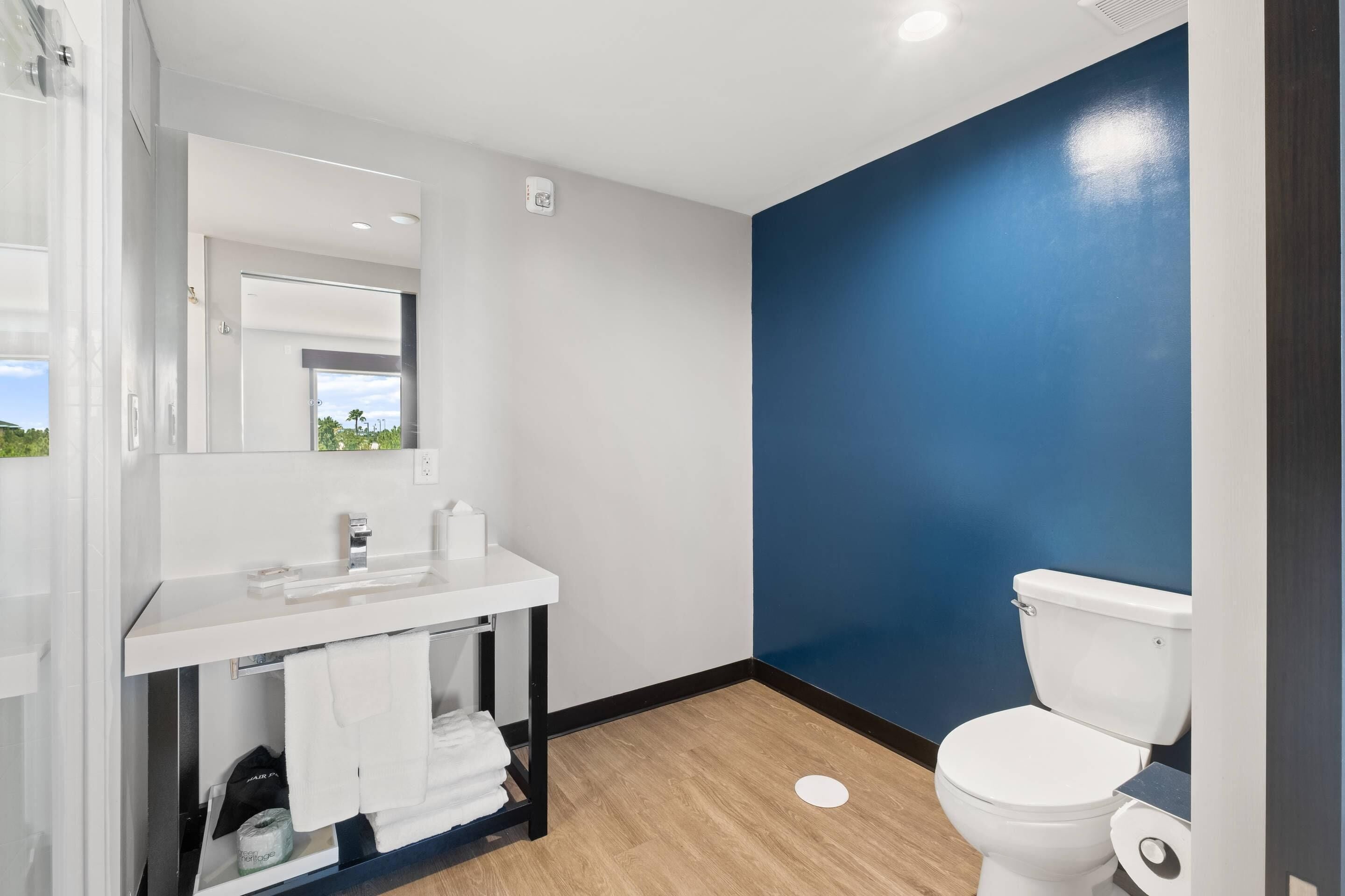 A modern bathroom with a white sink, mirror, and toilet.