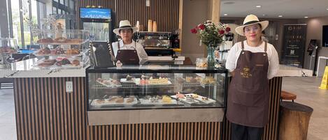 Un comptoir de boulangerie avec des pâtisseries, une machine à café et une grande fenêtre.