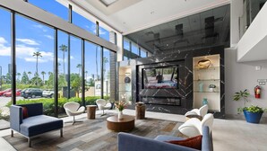 Un vestíbulo moderno con ventanas amplias, una chimenea y asientos cómodos.