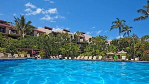 A hotel with a swimming pool, palm trees, and a clear blue sky. - Ground Floor Condo w/Kitchen - Kamaole Sands 3102 (Kihei)