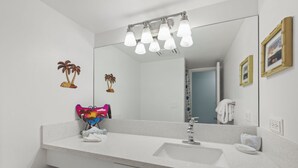 Ein Badezimmer mit einem weißen Waschbecken, einem Spiegel und einem Handtuchhalter.