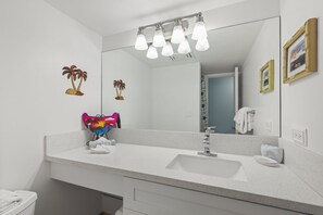 Ein Badezimmer mit einem weißen Waschbecken, einem Spiegel und einem Handtuchhalter.