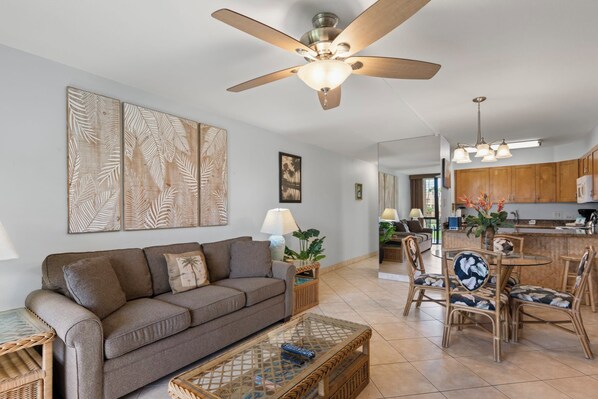 A living room with a sofa, coffee table, and dining area with chairs.