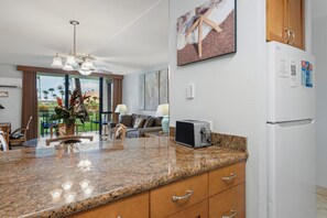 A kitchen with granite countertops, a toaster, and a refrigerator.