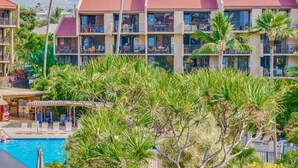 A hotel with multiple balconies, a swimming pool, and tropical landscaping. - Kamaole Sands 1 BR Partial Ocean View #2-302 (KIHEI)